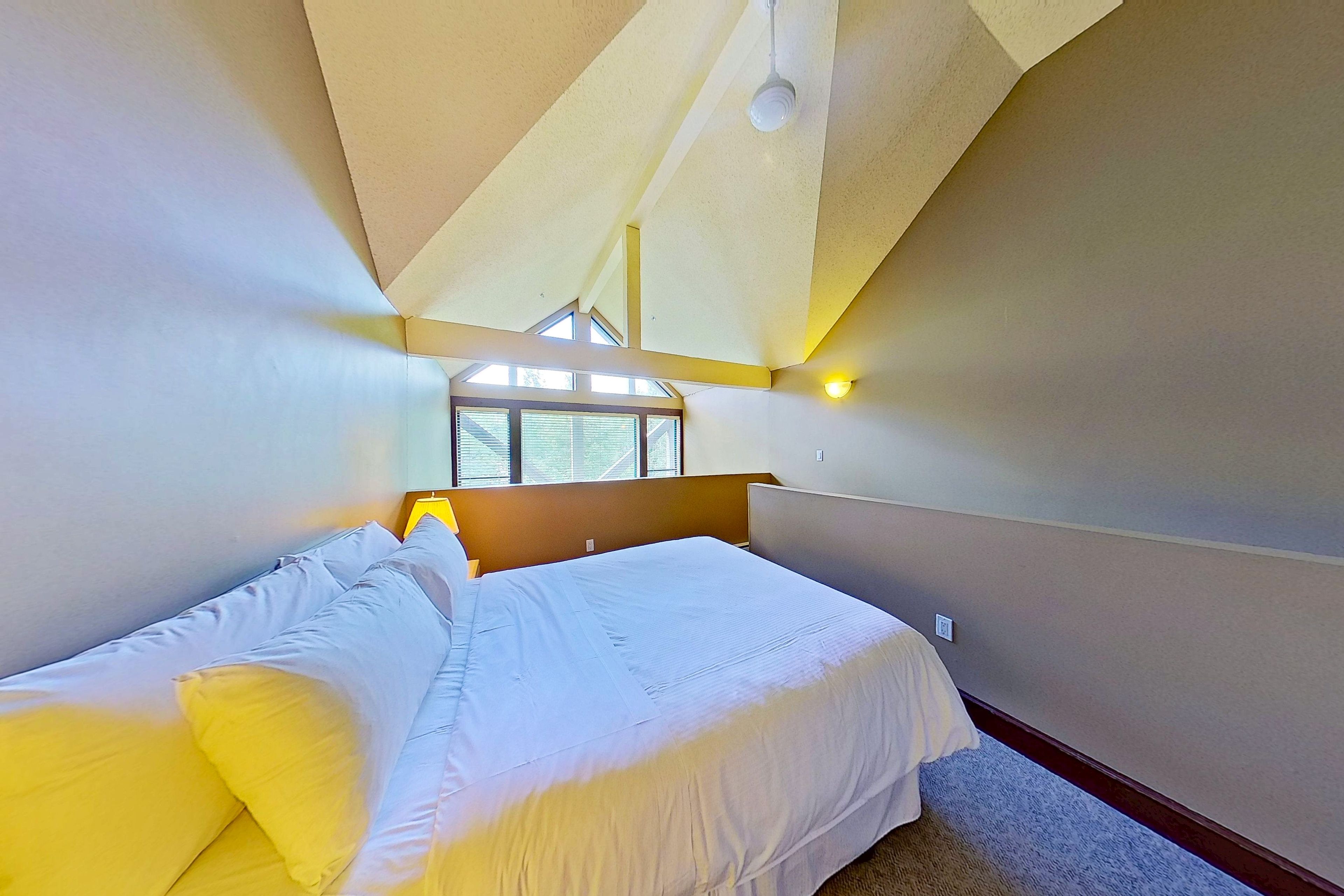 A bedroom with a bed, a window, and a ceiling light.