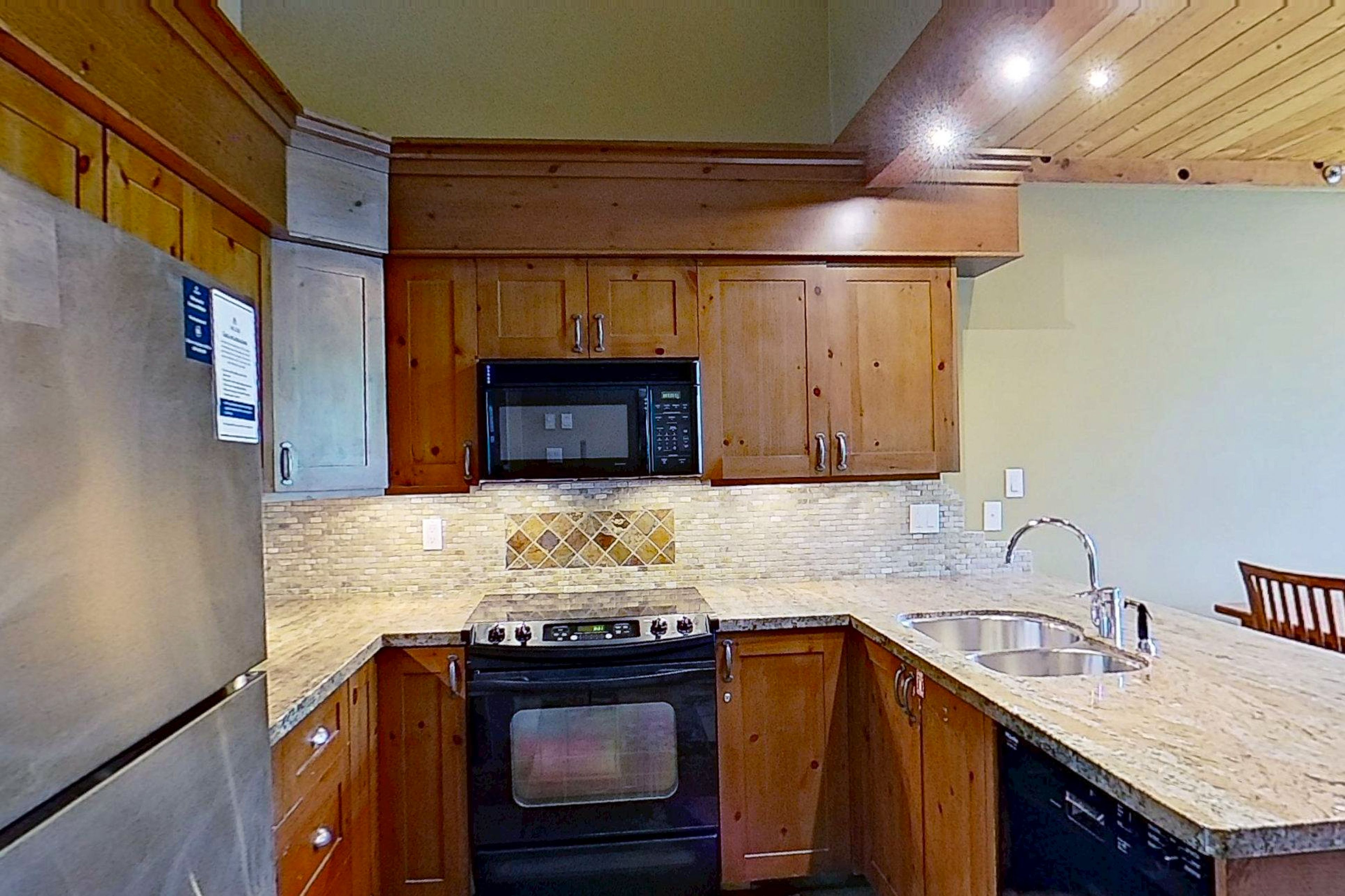 A kitchen with wooden cabinets, a microwave, a stove, and a sink.