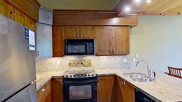 A kitchen with wooden cabinets, a microwave, a stove, and a sink.