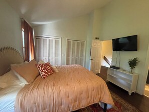 Une chambre à coucher avec un lit, un téléviseur fixé au mur et une porte donnant sur un placard.