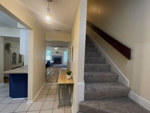 Une cuisine moderne avec un plan de travail bleu, une table à manger en bois agrémentée d’une plante, et un escalier menant à un autre niveau.