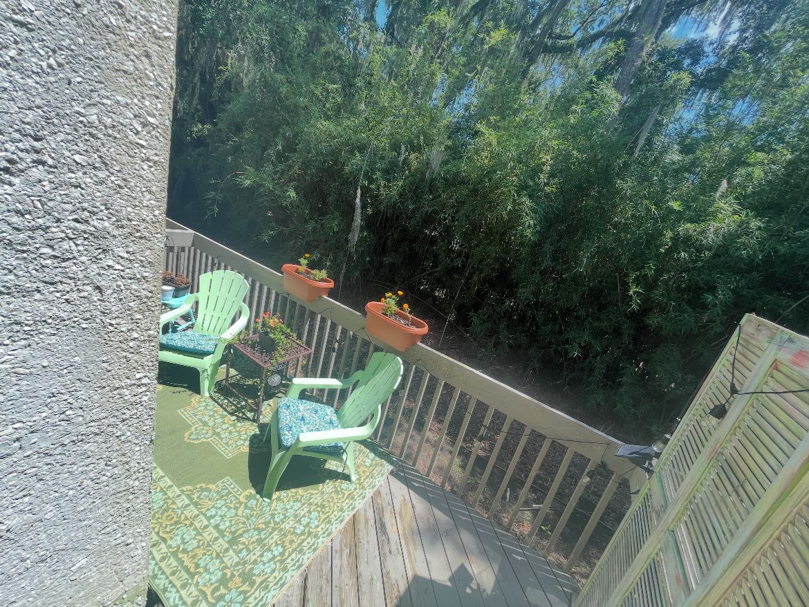Eine Holzterrasse mit Gartenmöbeln und Pflanzen in Töpfen.