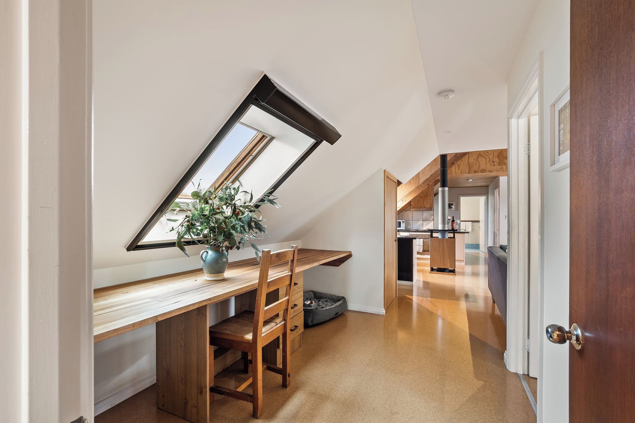 A compact kitchen with a skylight, wooden furniture, and a view into the adjacent living area.