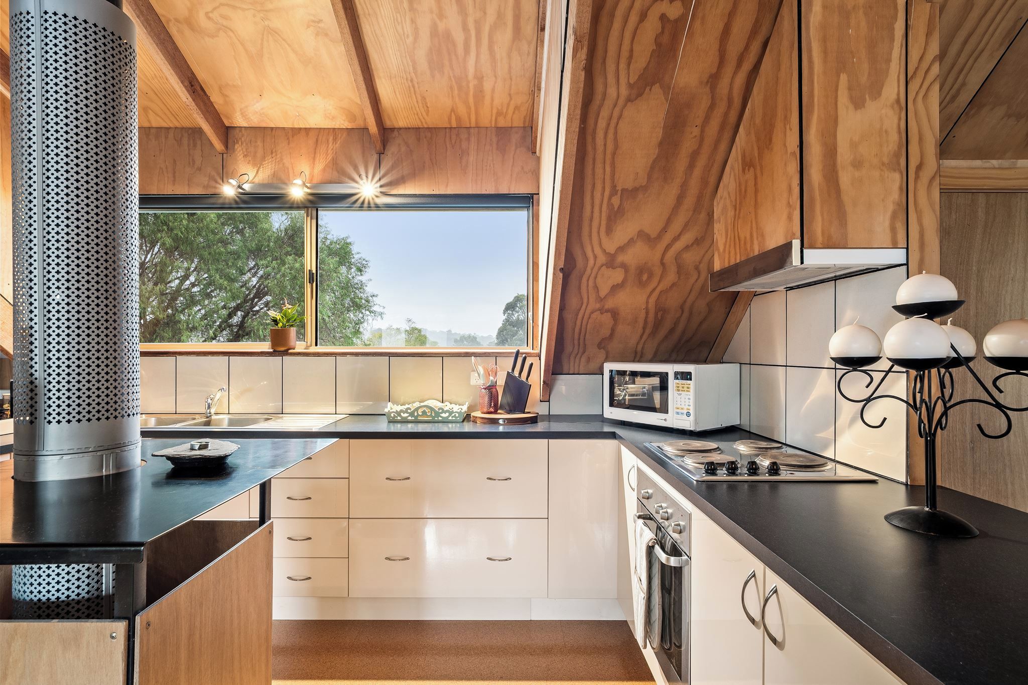 A modern kitchen with a large window, a built-in stove, and a microwave.