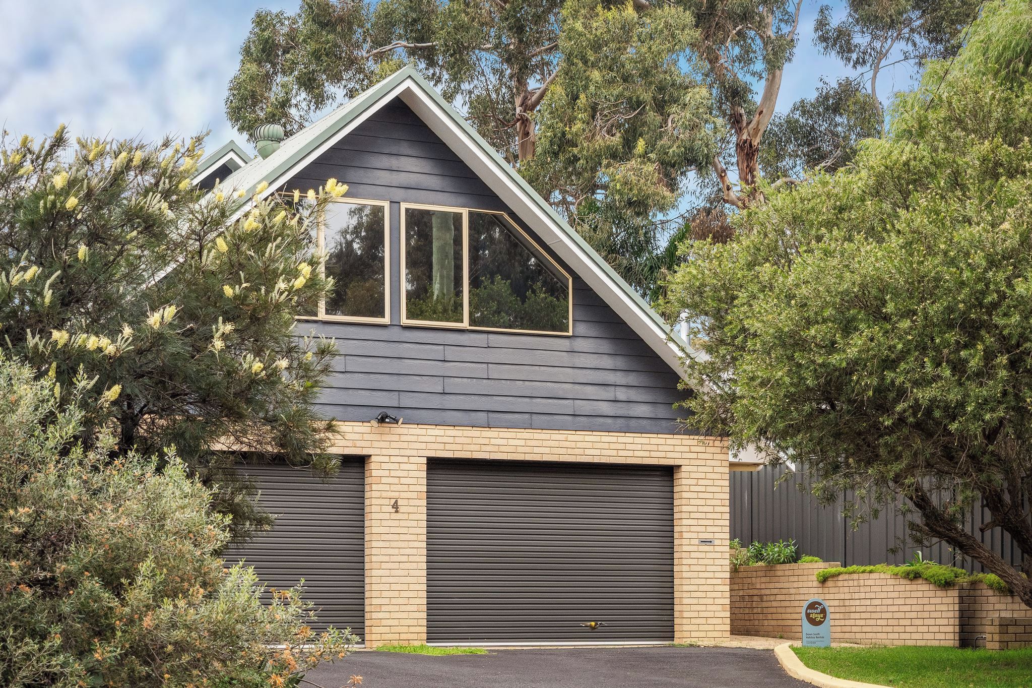 A residential house with a garage, a sloped roof, and a brick facade.