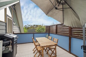A patio with a table and chairs, a barbecue grill, and a large umbrella providing shade. - Bella's Loft - Between Town and Trails (Margaret River)