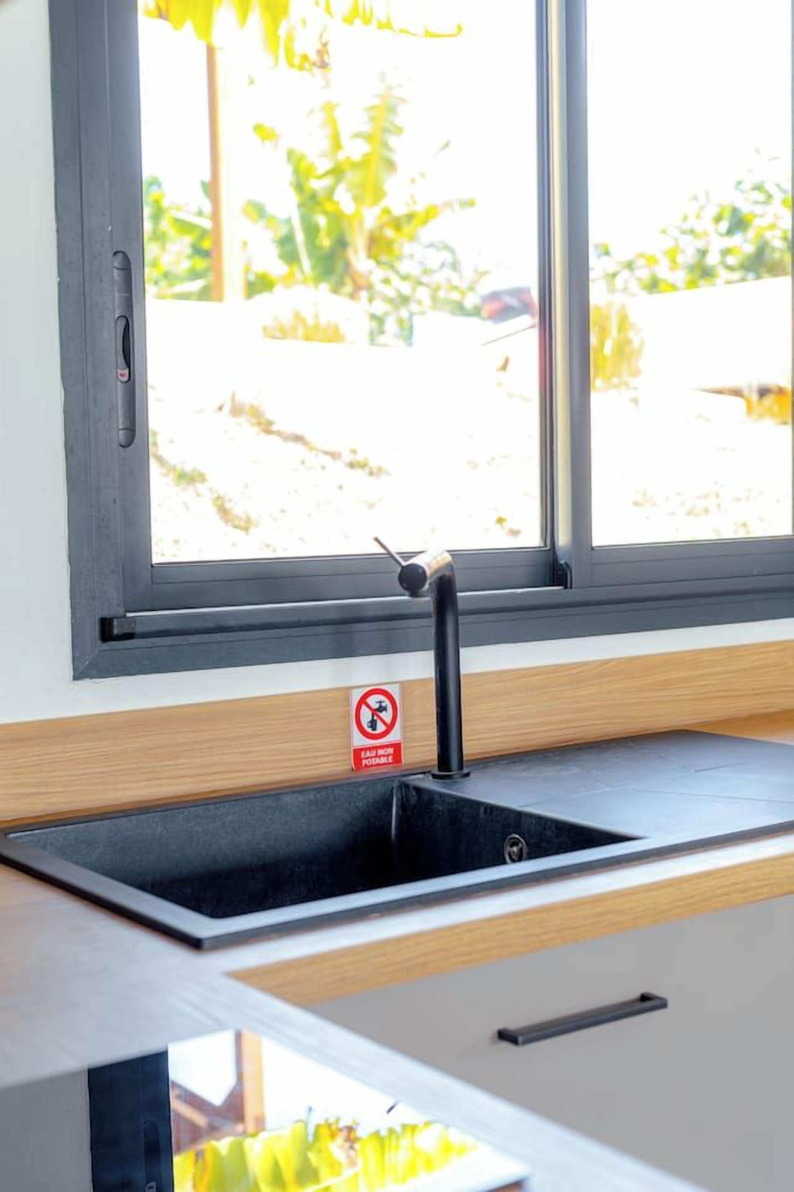 A kitchen with a black sink, a window, and a no smoking sign.