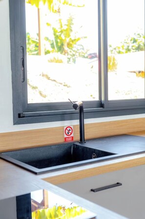 Eine Küche mit einem schwarzen Spülbecken, einem Fenster und einem Rauchverbot-Schild.