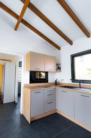A modern kitchen with wooden beams, light-colored cabinets, and a black countertop. - Sahari: 3-bedroom apartment with private pool, centrally located and quiet (Les Abymes)