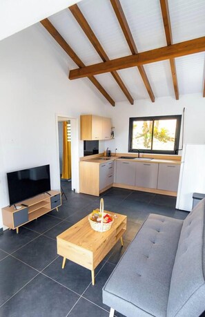 A modern living room with a sofa, a TV, and a wooden coffee table. - Sahari: 3-bedroom apartment with private pool, centrally located and quiet (Les Abymes)