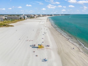 An aerial view of a beach with a lifeguard tower, beach umbrellas, and a clear sky. - Spacious 4BR Villa on Siesta Key w/ Private Screened Pool & Lanai (Siesta Key)