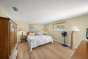 A bedroom with a bed, bedside lamps, a standing fan, a wooden wardrobe, and a window with blinds. - Spacious 4BR Villa on Siesta Key w/ Private Screened Pool & Lanai (Siesta Key)