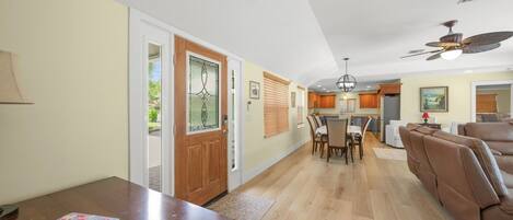 A spacious living area with a dining table, a sofa, and a kitchen in the background.
