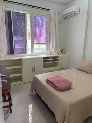 A bedroom with a bed, a desk, a window with curtains, and an air conditioner. - Fantastic 3-bedroom apartment with AC in vibrant Rio de Janeiro (Rio de Janeiro)