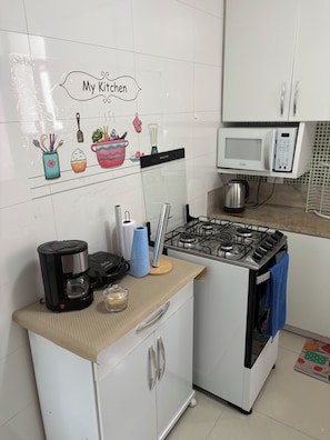 Eine Küche mit einem Gasherd, einer Kaffeemaschine, einer Mikrowelle und einem Schrank mit dem Schild 'My Kitchen'.