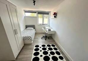 A small, narrow room with a bed, a desk, and a chair. There is a window providing natural light. - Foresthill 3-bed Home, Sleeps 5 With Parking (London)