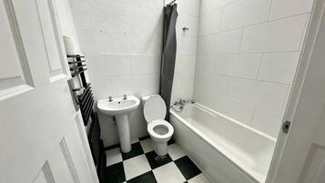 Une petite salle de bain avec des toilettes, un lavabo et une baignoire.