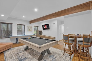 A pool table with a billiards cue rack, a television mounted on the wall, and a dining table with chairs. - Hot Tub, Luxe, Game Room, Open Concept, Privacy (Tobyhanna Township)