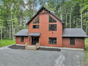 A two-story wooden cabin with a front porch and a gravel driveway. - Hot Tub, Luxe, Game Room, Open Concept, Privacy (Tobyhanna Township)