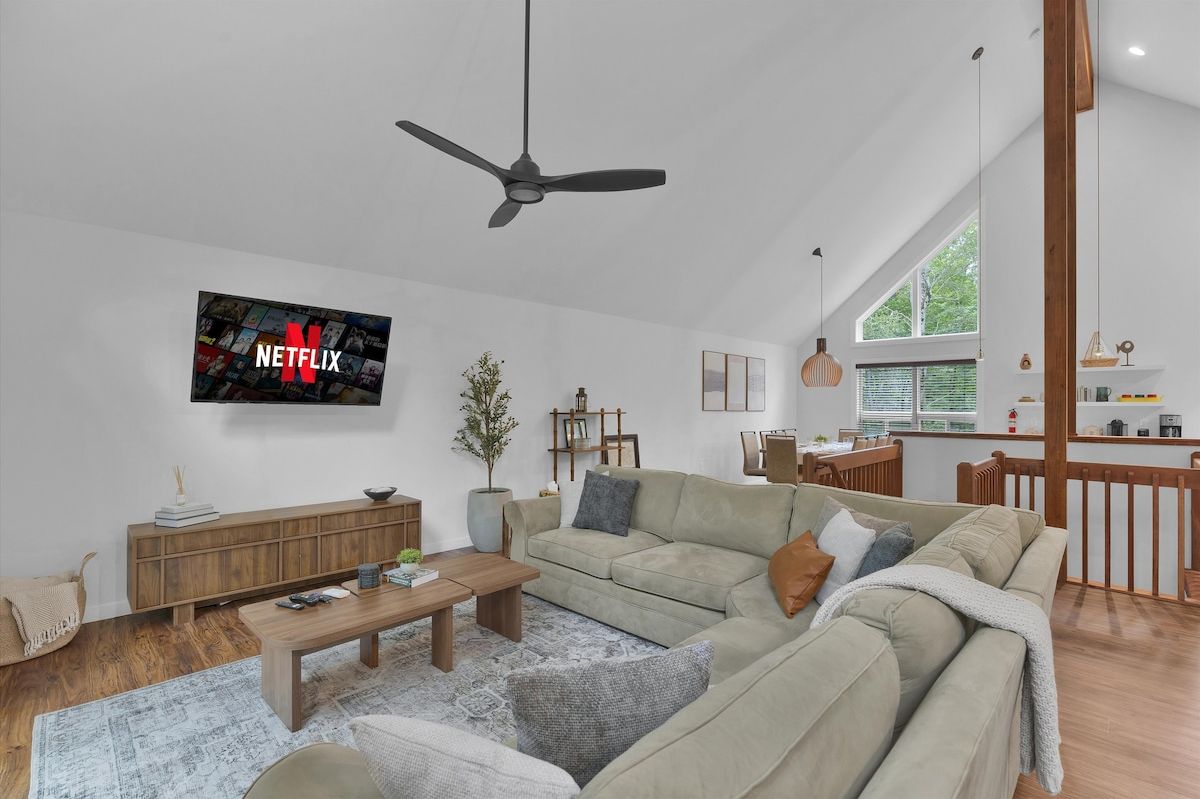 A modern living room with a sofa, coffee table, and a TV displaying the Netflix logo.