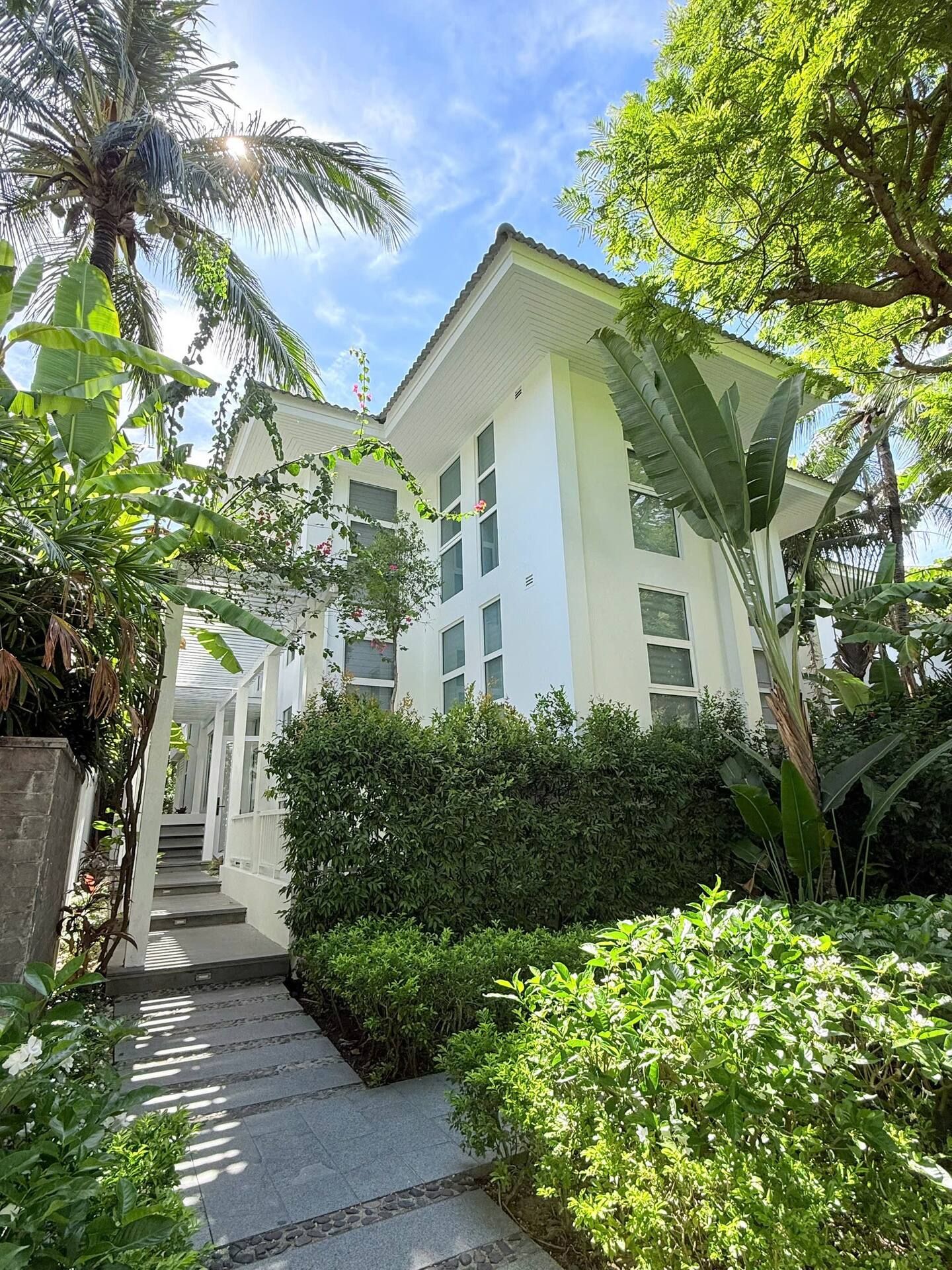 A building with a covered walkway, surrounded by lush greenery and palm trees.