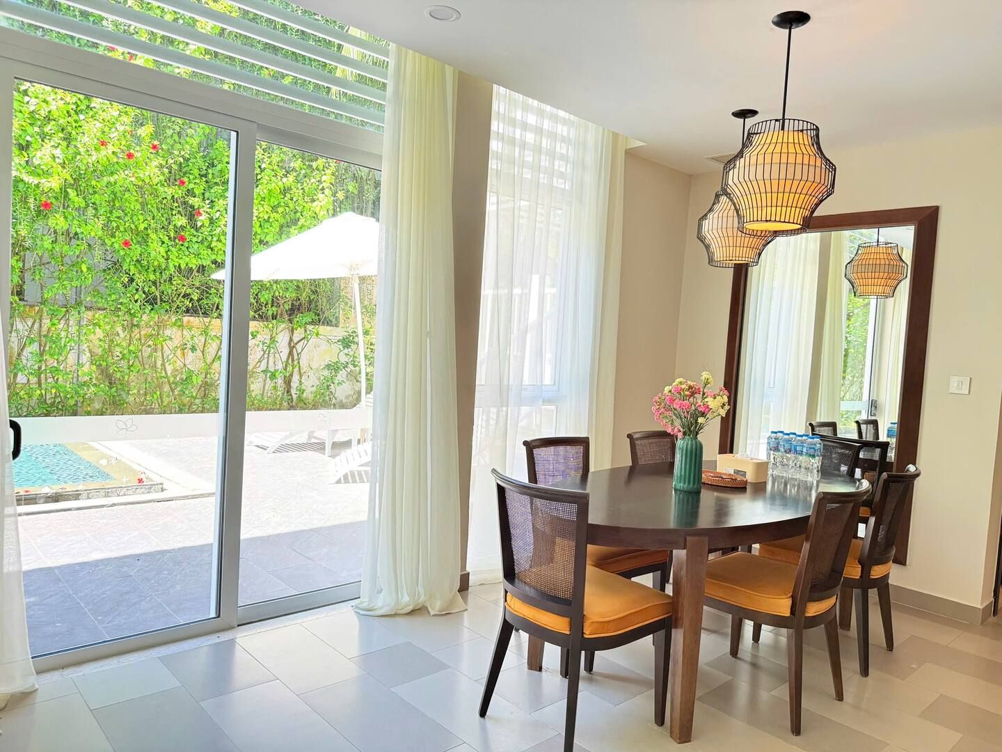 A dining area with a round table, chairs, and a vase of flowers.