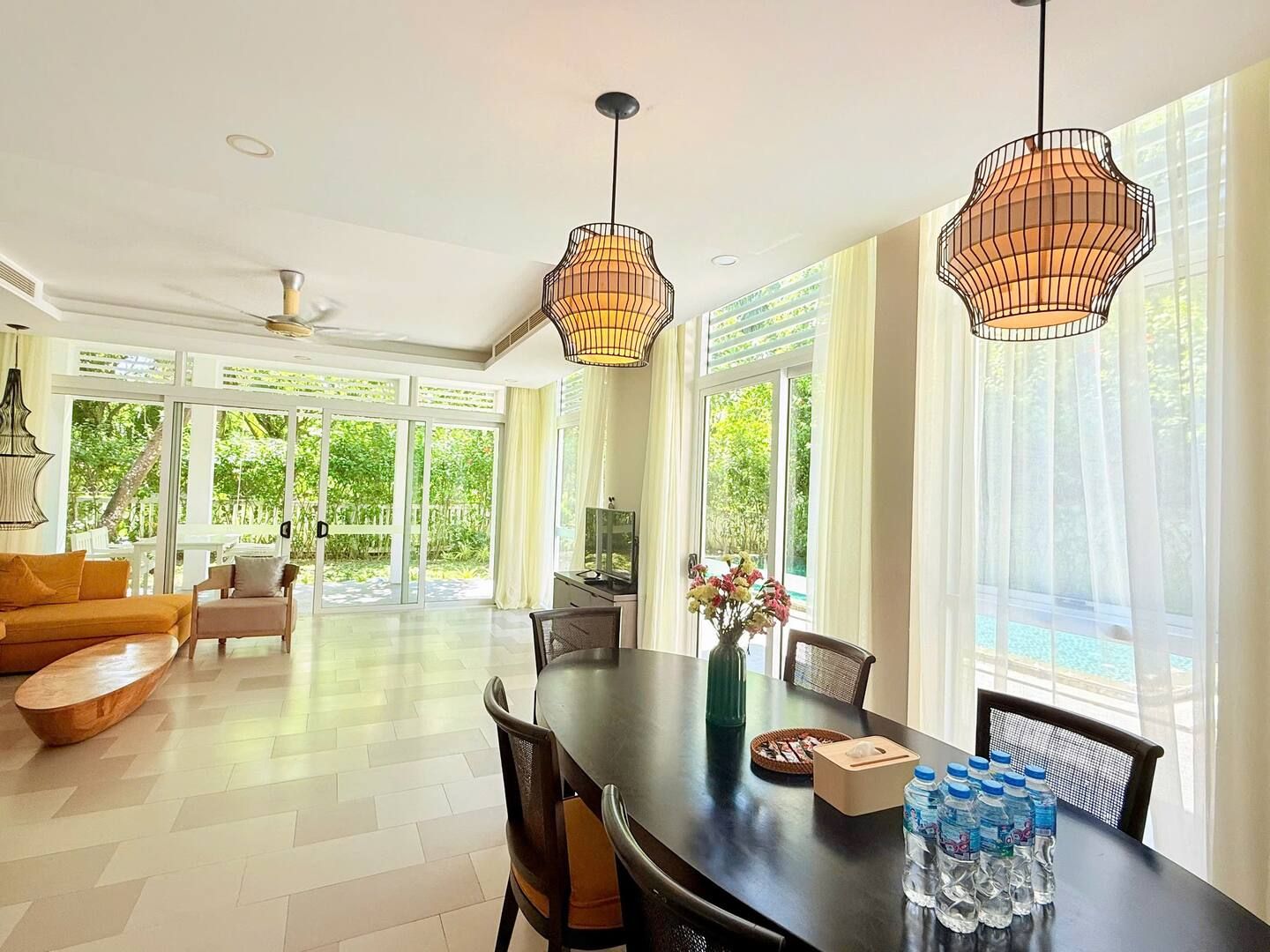 A spacious dining area with a large table, chairs, and pendant lighting.