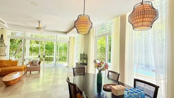 A spacious dining area with a large table, chairs, and pendant lighting.