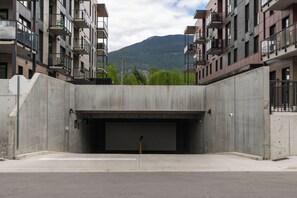 Ein modernes Gebäude mit einem zentralen Garageneingang, umgeben von Hochhauswohnungen mit Balkonen.