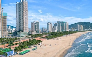 Eine Küstenstadt mit Hochhäusern, einem Sandstrand und wolkenlosem Himmel.