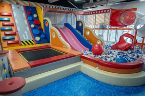 Ein Spielbereich mit Trampolin, Rutschen und Bällebad.