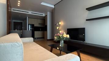 A modern living room with a sofa, a coffee table, a TV, and a vase with flowers.
