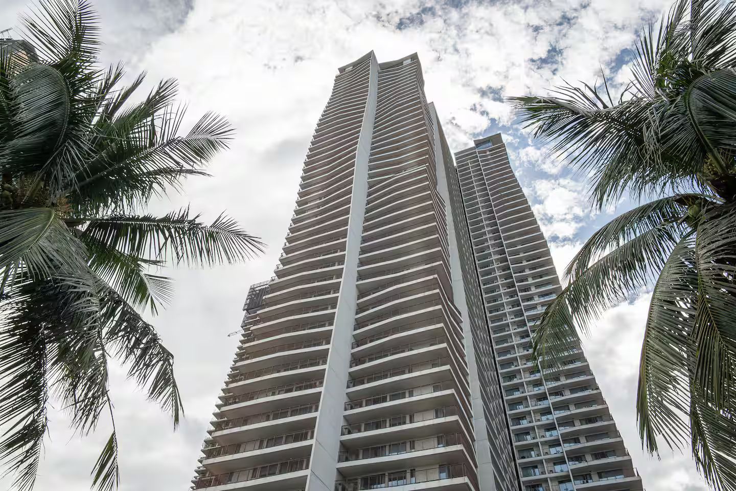 Un edificio alto con varios balcones, rodeado de palmeras.