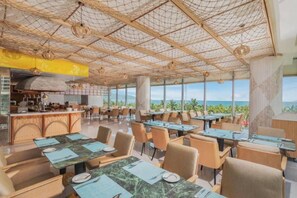 A spacious restaurant with a high ceiling and large windows offering a view of the ocean. - @Discount 20% & 2 Bed Rooms Luxury #Ocean View! (Đà Nẵng)