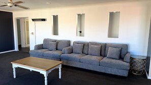 Un salon avec un canapé gris, une table basse en bois et une petite table d’appoint en métal servant de décoration.