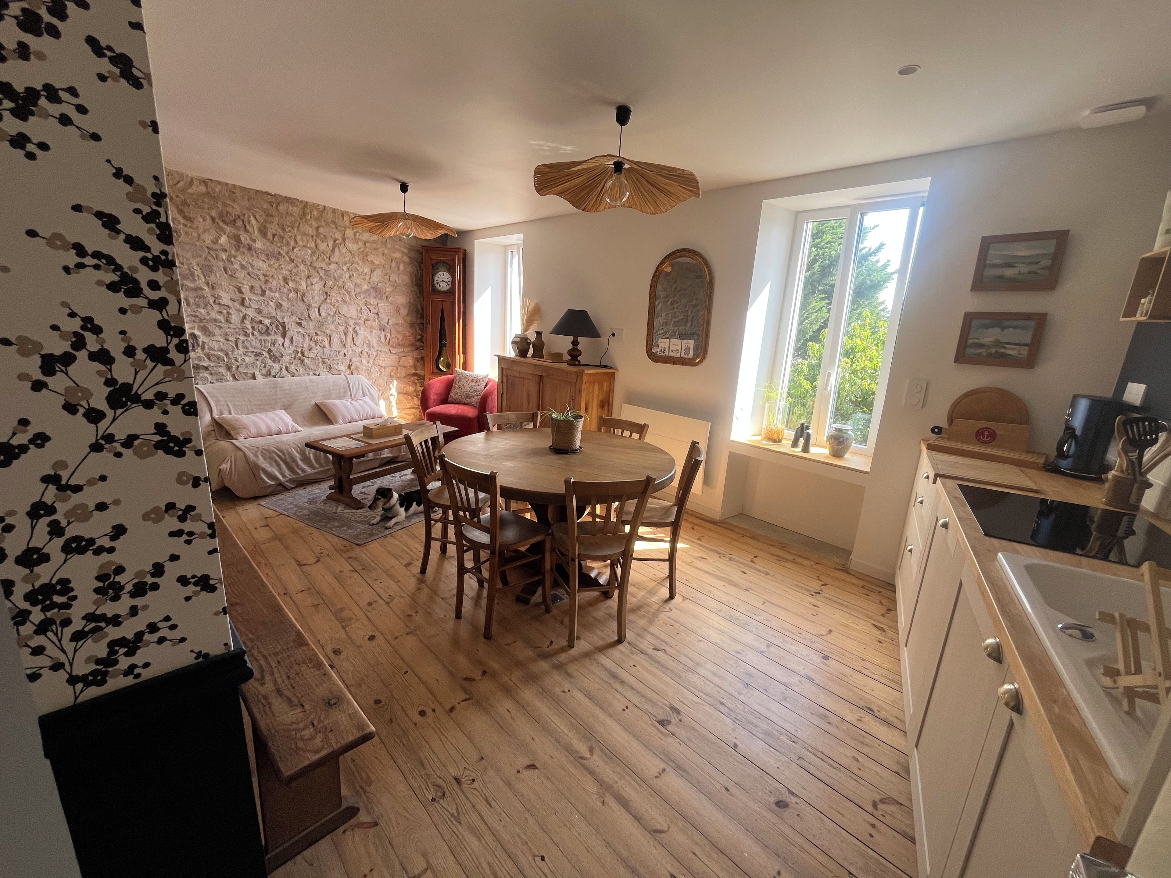 Un salón acogedor con pared de piedra, una mesa de comedor de madera y un sillón rojo.