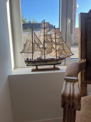 A model ship on a white shelf by a window. - The Little Pink Sandstone House “Ti Lulu”—A charming fisherman’s cottage with a view of the sea (Erquy)