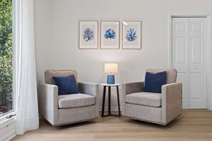 A room with two armchairs, a small table with a lamp, and three framed wall art pieces. - Players Club Getaway I Sawgrass (Palm Valley)