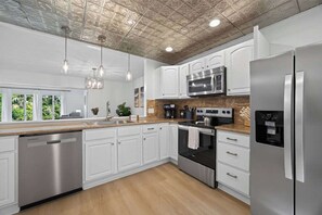 A modern kitchen with stainless steel appliances, white cabinetry, and a wooden countertop.