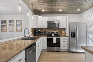 A modern kitchen with white cabinetry, stainless steel appliances, and a granite countertop. - Players Club Getaway I Sawgrass (Palm Valley)