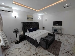 Une chambre moderne avec un grand lit, des tables de chevet, un bureau et un téléviseur.