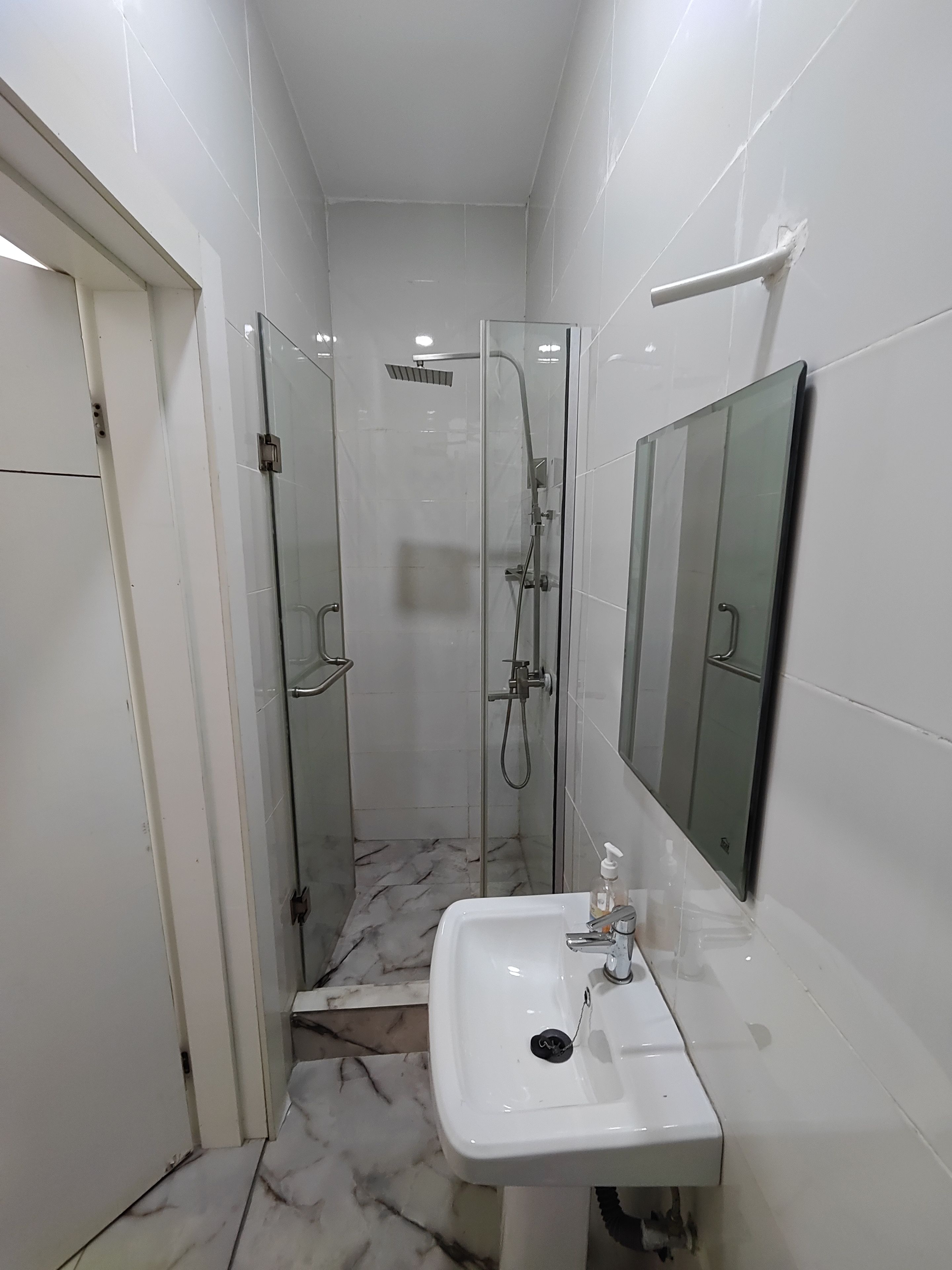 Une salle de bain avec une douche à parois de verre, un lavabo blanc et un miroir.