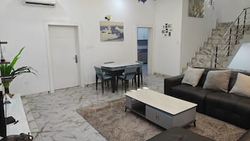 Ein modernes Wohnzimmer mit einer Couch, einem Couchtisch und einem Essbereich mit Stühlen.