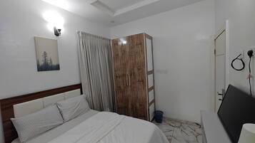 Ein Schlafzimmer mit einem Bett, einem Kleiderschrank, einem Schreibtisch und einer Wandleuchte.