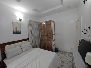 Un dormitorio con cama, armario, escritorio e iluminación en la pared.