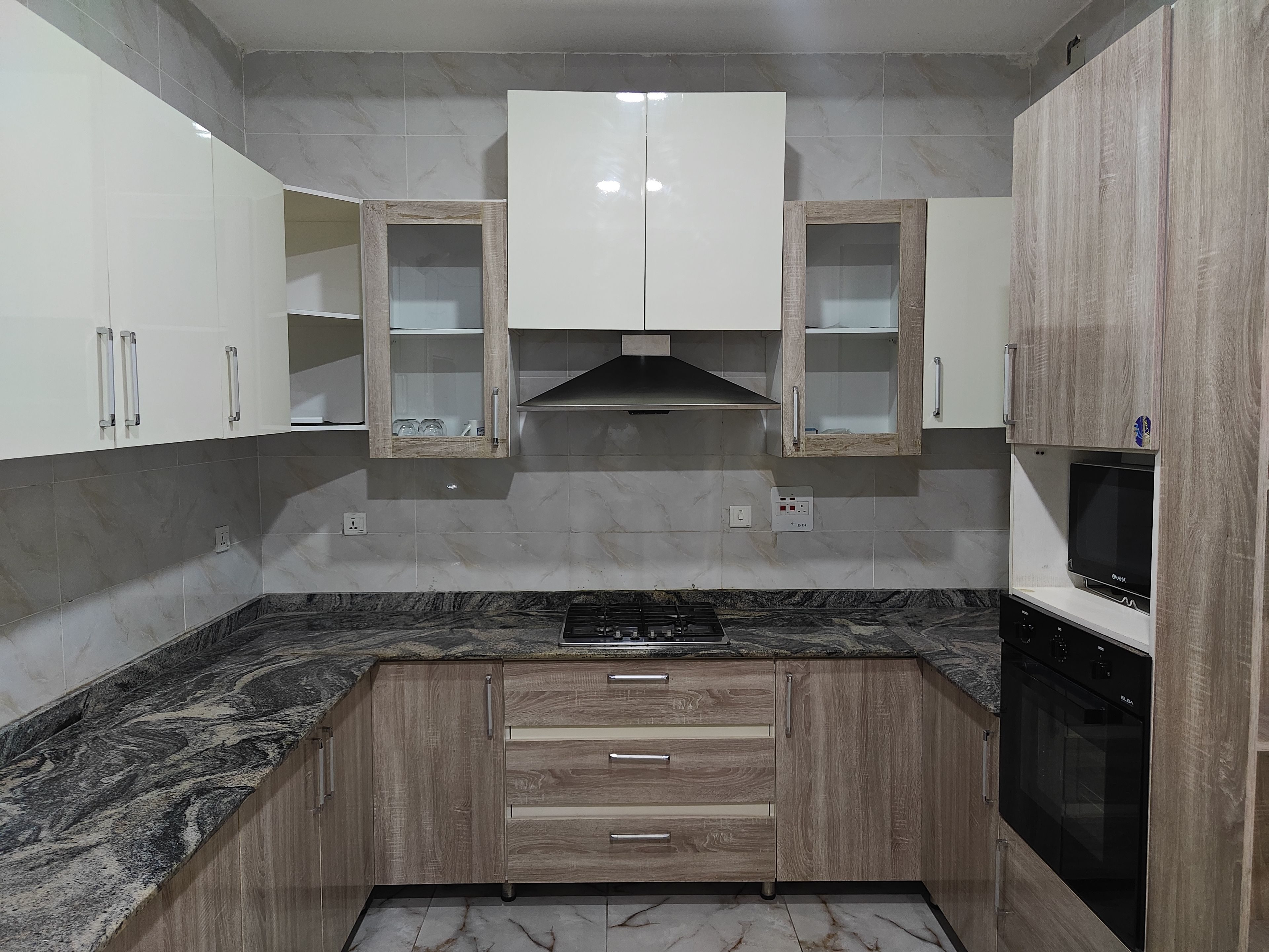 Una cocina con encimeras de mármol, armarios de madera y horno empotrado.