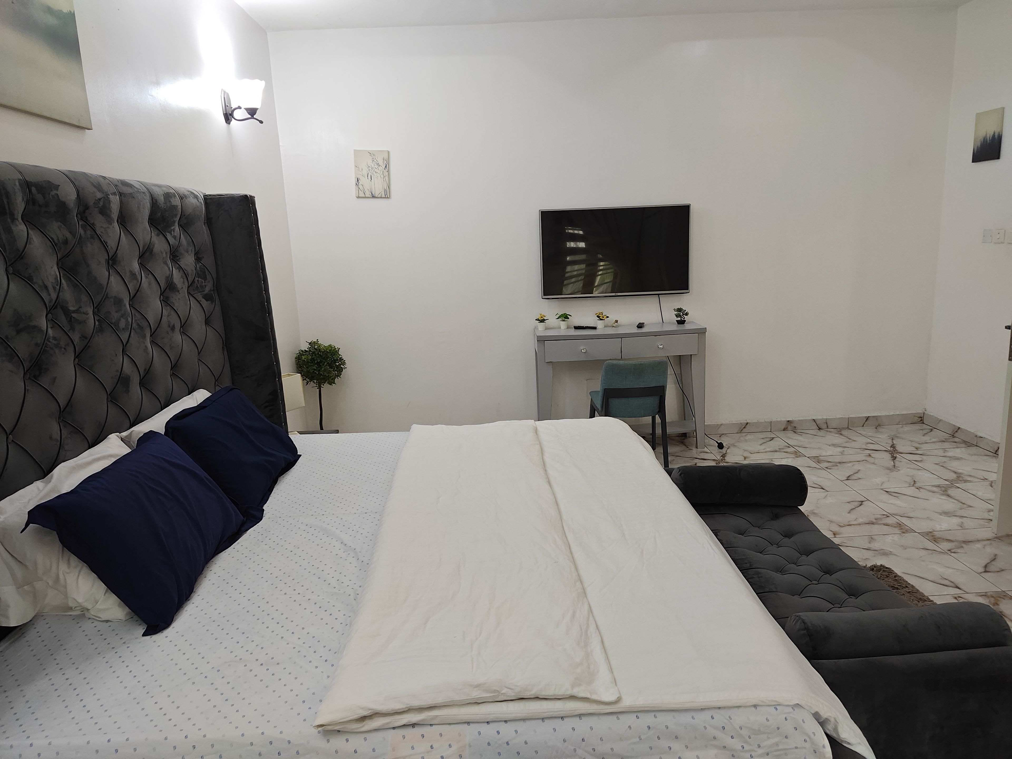 Un dormitorio con una cama, un escritorio, una silla y un televisor.