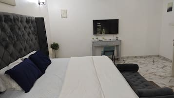 A bedroom with a bed, a desk, a chair, and a television.