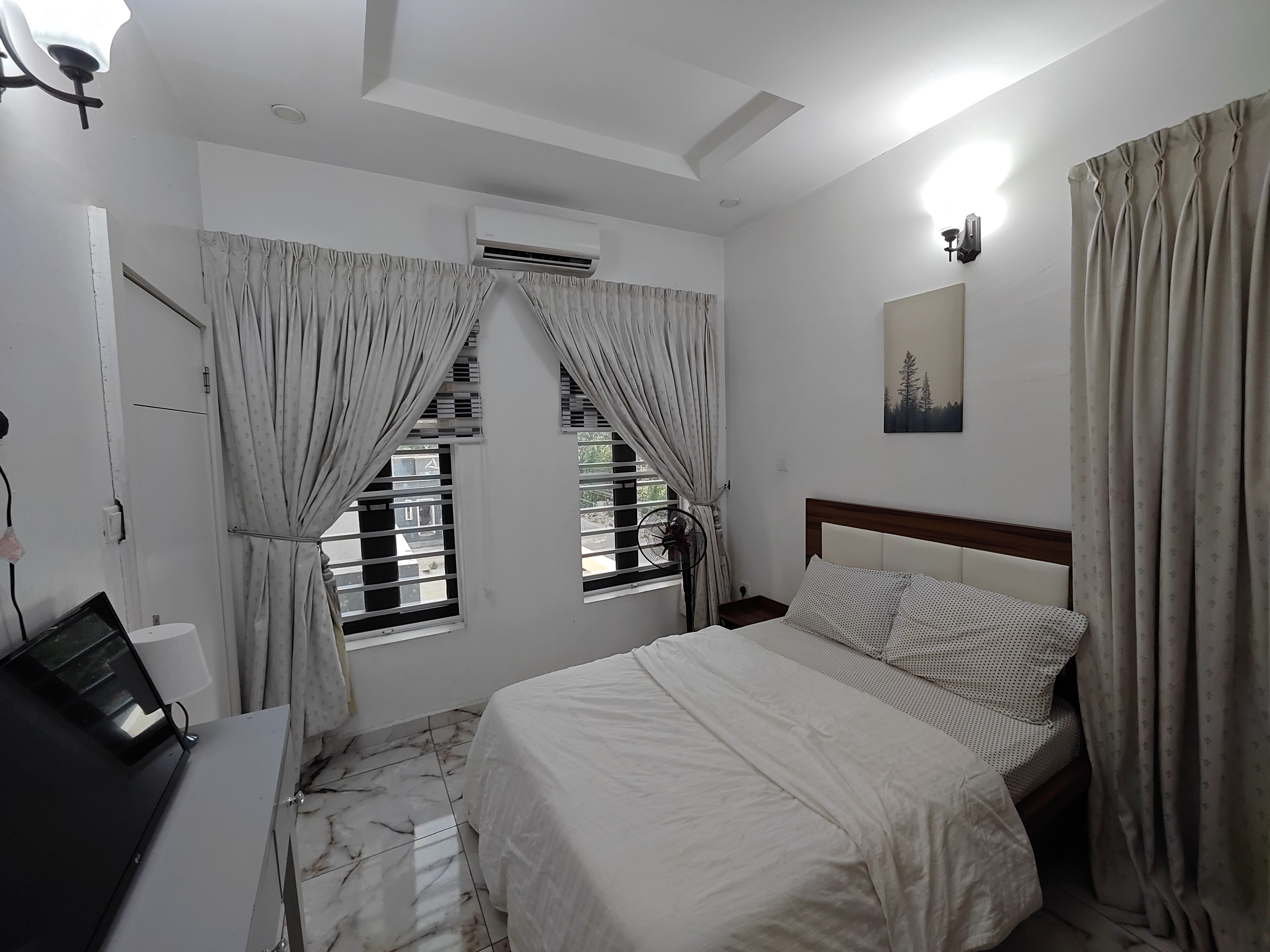 Una camera da letto con un letto, una scrivania e una finestra con tende.