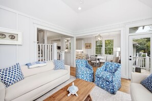 Un salon spacieux avec un canapé blanc, des fauteuils à motifs et une table basse en bois.